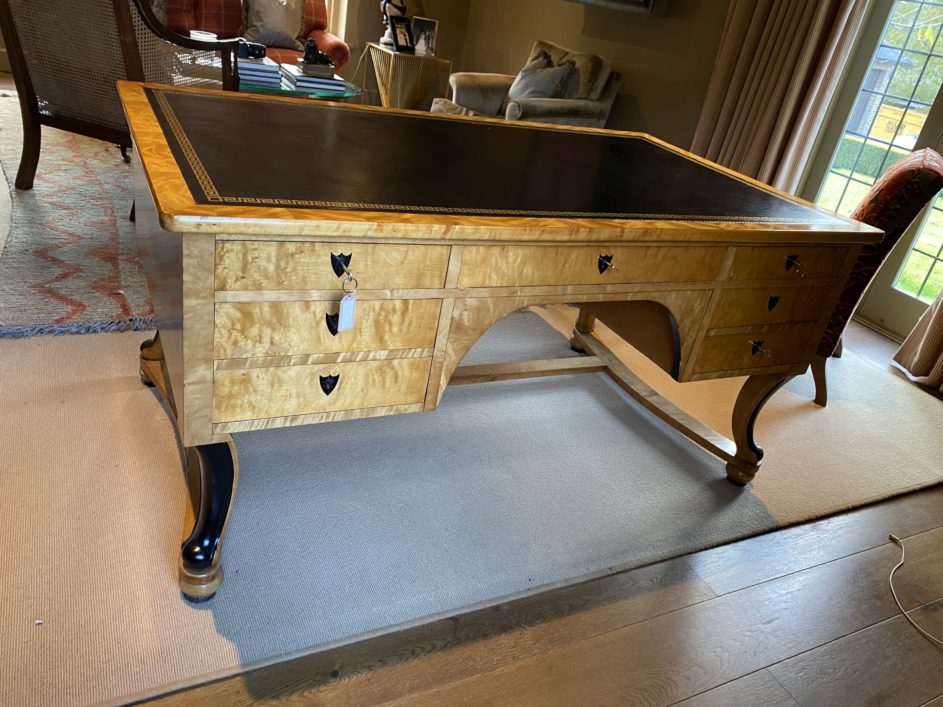 A Biedermeier style maple desk, with black leather skiver and seven drawers, on ebonised scroll legs with H stretcher, width 155cm depth 91cm height 76cm